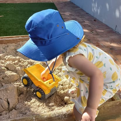A child playing with a toy truck in the sandpit